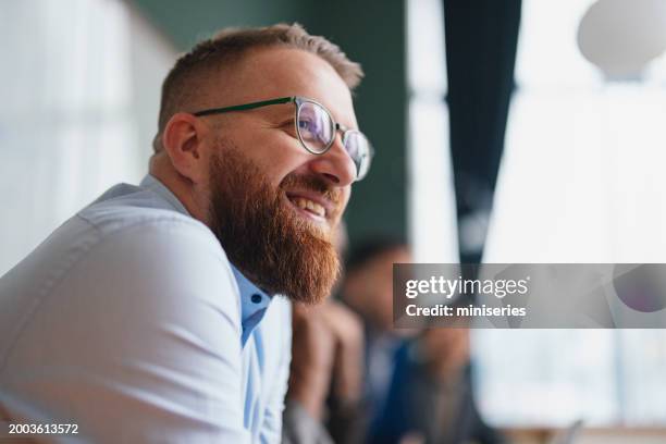 lächelnder bärtiger mann mit brille bei einem zwanglosen geschäftstreffen - zufriedenheit stock-fotos und bilder