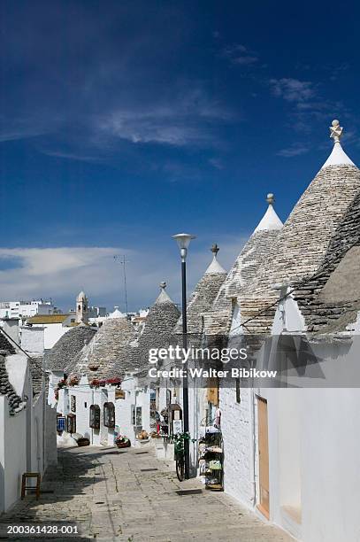 italy, puglia, alberobello, street lined with trulli houses - alberobello foto e immagini stock