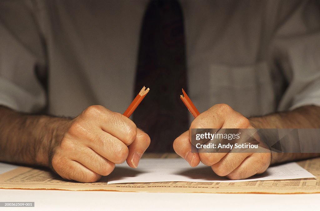 Stressed man breaking pencil, (Mid section)