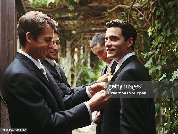 groomsman adjusting groom's boutonniere - bräutigam stock-fotos und bilder