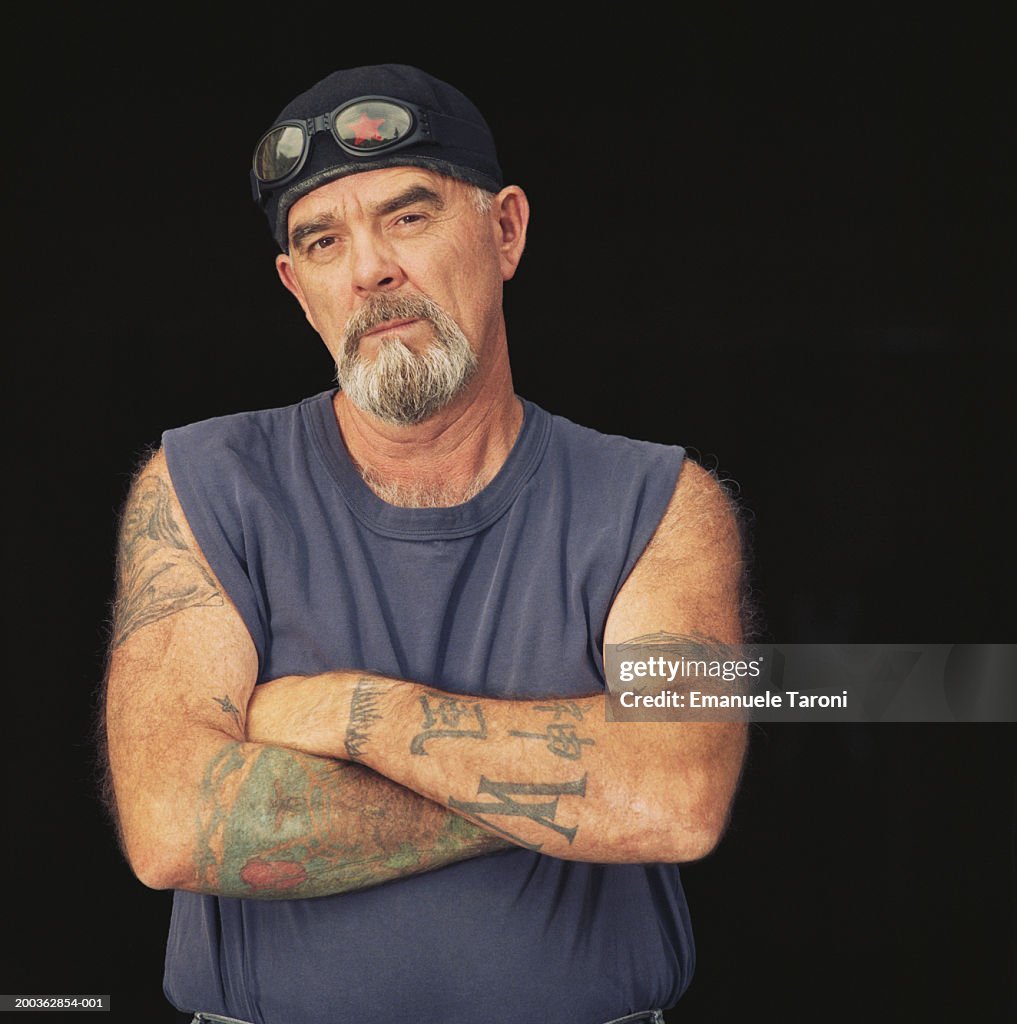 Mature man with tattooed arms, arms crossed, portrait