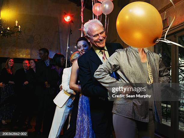 mature couple leading conga line on dance floor - faire la chenille photos et images de collection