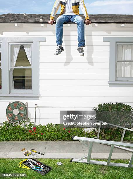 man sitting on roof of house, ladder on lawn - immobilie humor stock-fotos und bilder