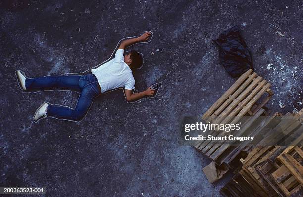 man with gun lying on ground, chalk outline around him, elevated view - silhouette à la craie photos et images de collection