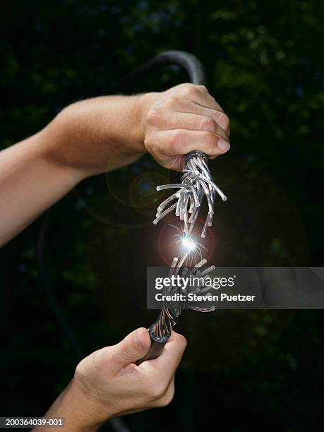 person touching two cables together, creating spark - wire cut stockfoto's en -beelden