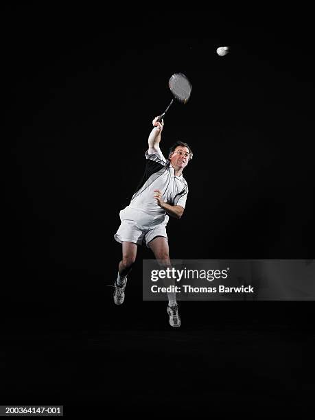 mature man hitting shuttlecock with badminton racket - playing badminton stock-fotos und bilder