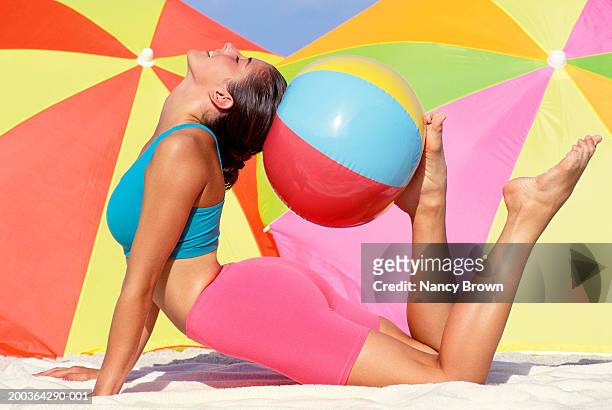 woman exercising on beach with beach ball, side view - ゴムボール ストックフォトと画像