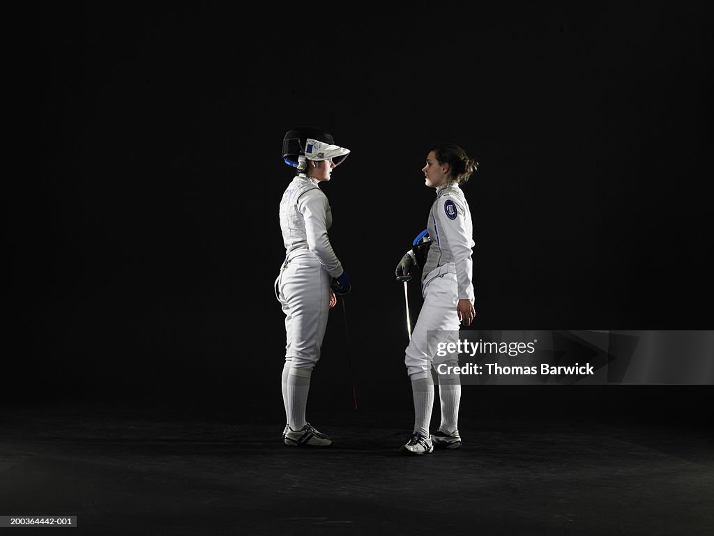 Two female (15-18) fencers facing off, side view
