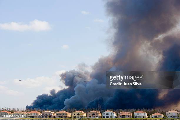helicopter near smoke caused by brush fire behind houses - forest fire stockfoto's en -beelden
