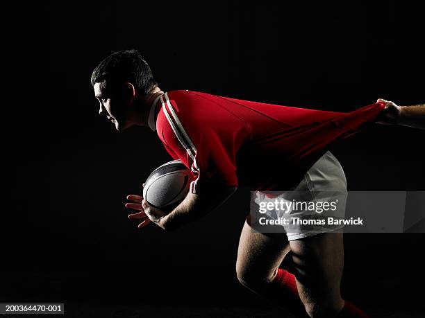 two young men playing rugby, one carrying ball, one pulling on jersey - rugby jersey stock-fotos und bilder