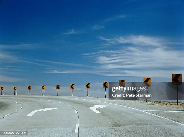 arrows on pavement and around bend in road - safety sign stock pictures, royalty-free photos & images