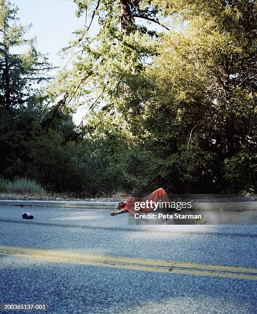 skateboarder lying by curb after crash - bordsteinkante stock-fotos und bilder