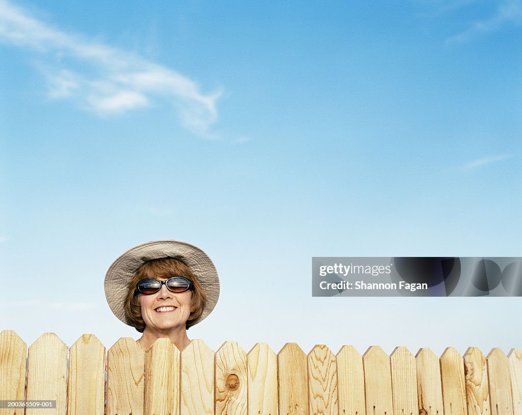 Mature woman looking over fence, smiling