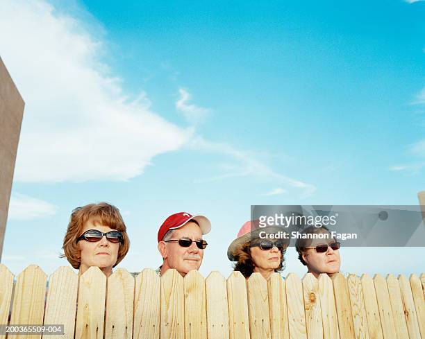 group of people looking over fence - fence stockfoto's en -beelden