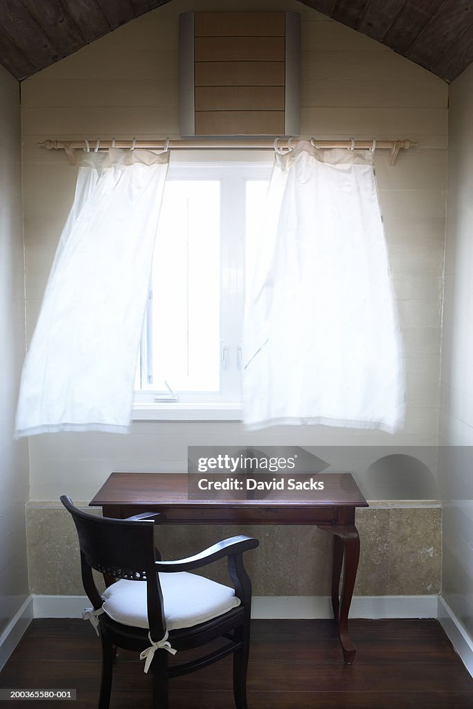Wind blowing through open window above desk