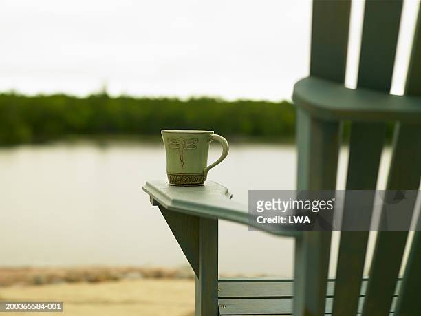 coffee mug on adirondack chair near lake, summer - adirondack chair closeup stock pictures, royalty-free photos & images
