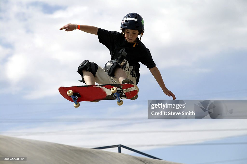 Boy (9-11) performing jump on skateboard, low angle view