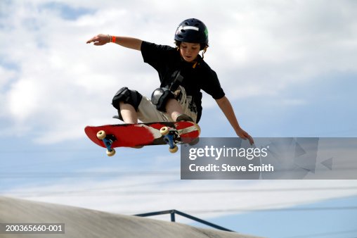 Boy (9-11) performing jump on skateboard, low angle view Boy (9-11) performing jump on skateboard, low angle view