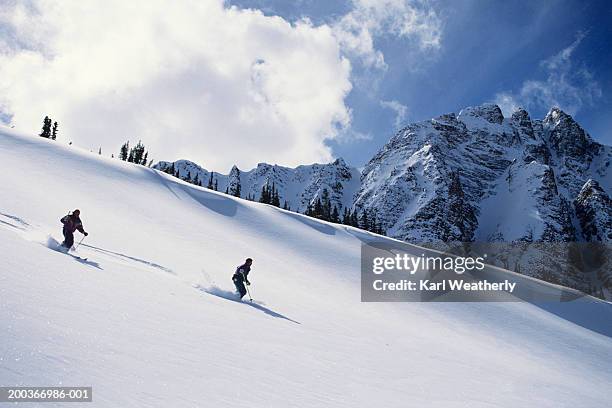 two skiers on ski slope, jasper national park, alberta, canada - jasper canada stock pictures, royalty-free photos & images