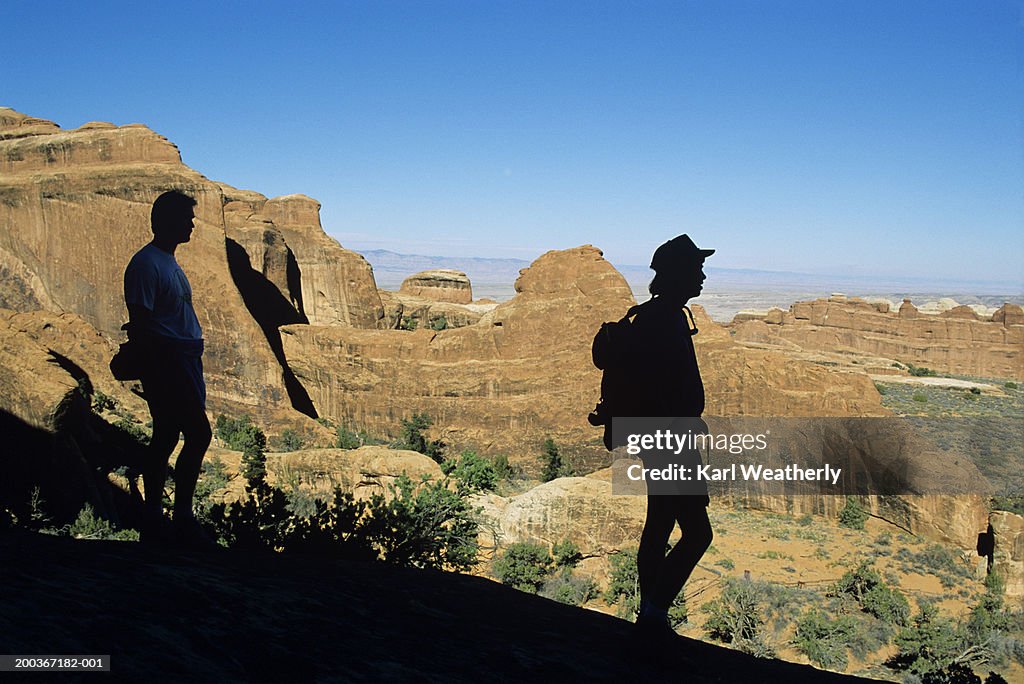 Two hikers seen as silhouettes in Arches National Park, Utah, USA