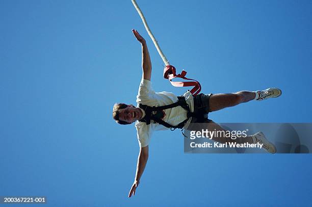 man bungee jumping, seen against blue sky, view from below - bungee jump - fotografias e filmes do acervo