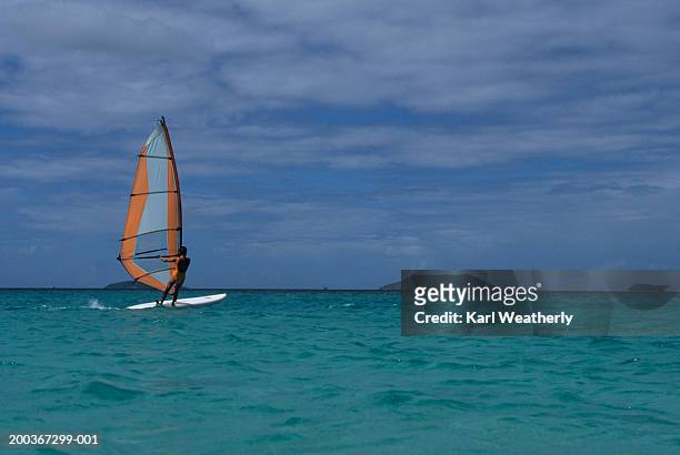 unrecognizable person windsurfing on bright blue water - windsurf stockfoto's en -beelden