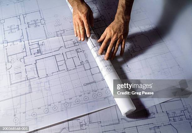 man unrolling architectural plans, close-up - architects design drawings stockfoto's en -beelden