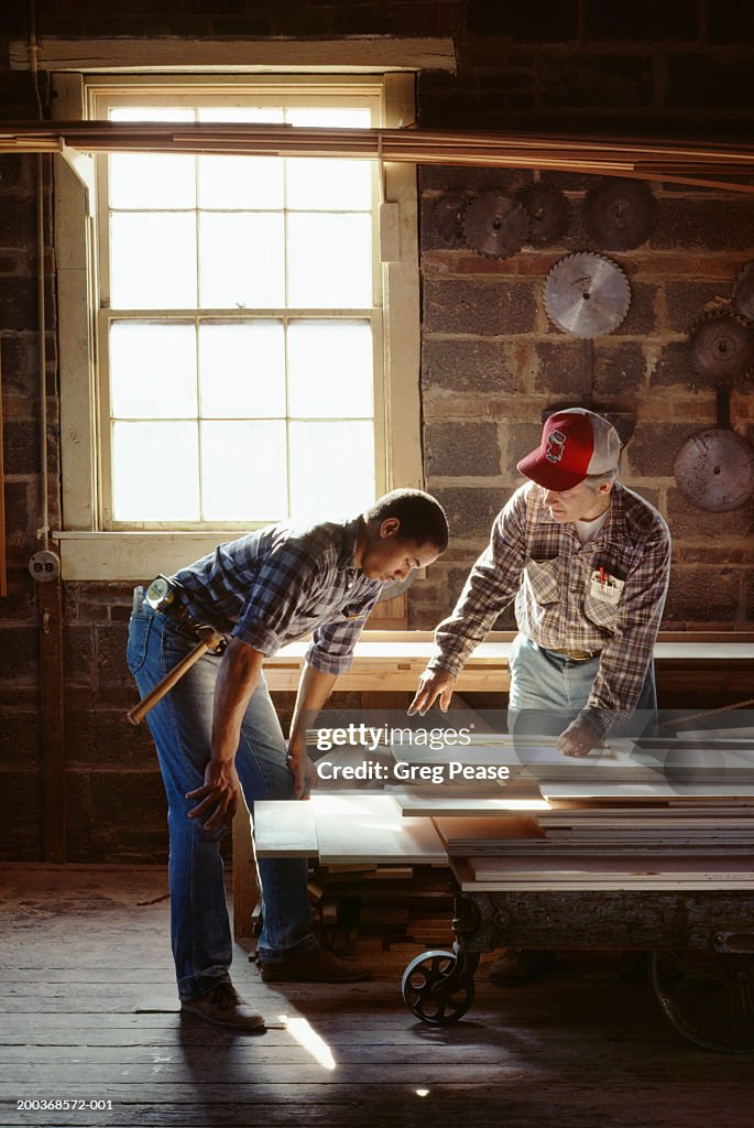 Mature and young men working in wood shop