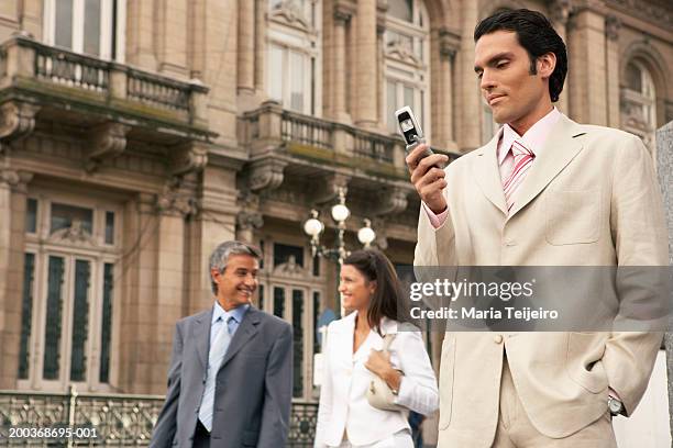 três empresários, homem usando telefone móvel, ângulo baixo - telefone-de-dobrar imagens e fotografias de stock