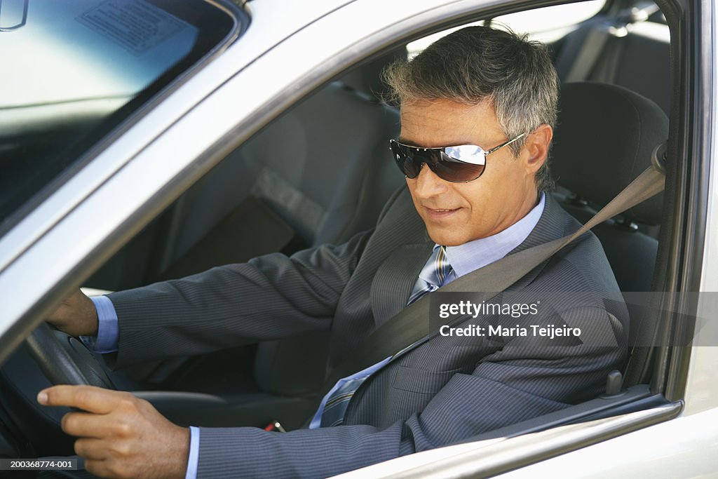 Businessman wearing shades in car, close up, elevated view