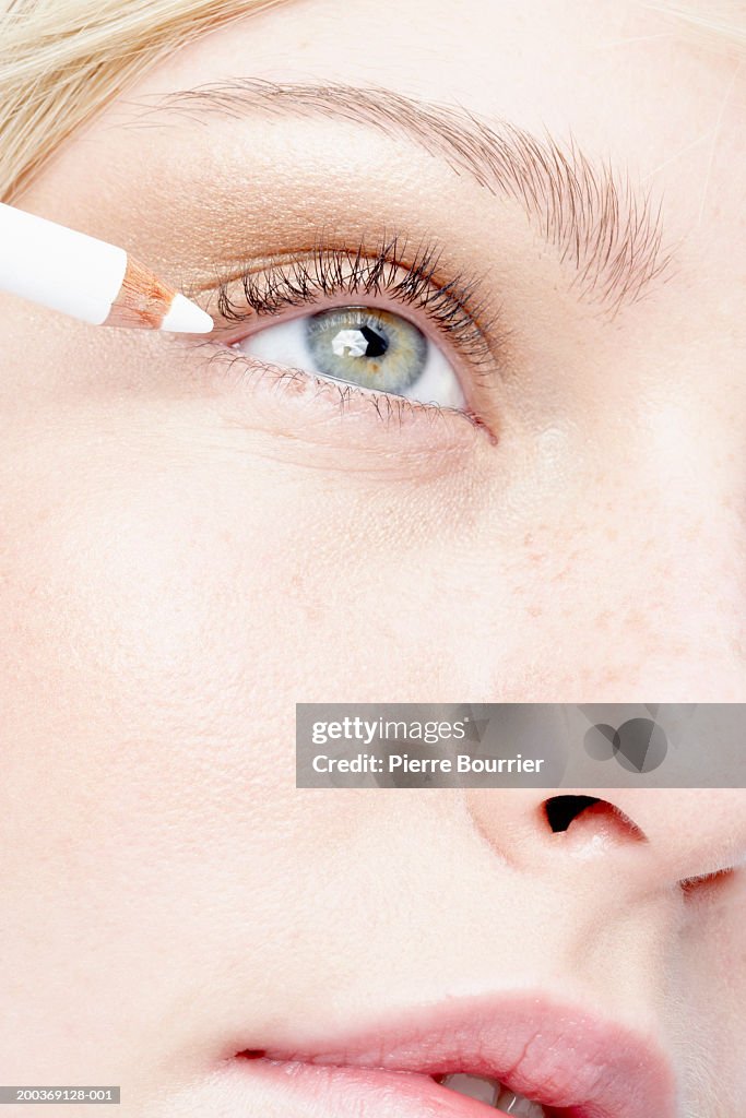 Young woman applying eyeliner, close-up