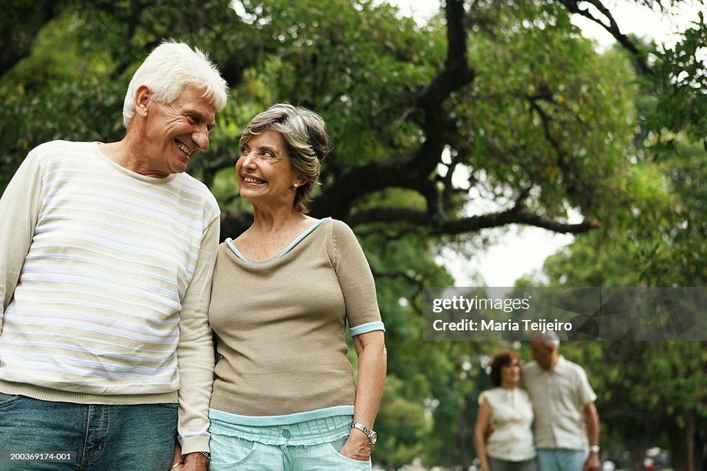 Senior couple in park, smiling, mature couple in background