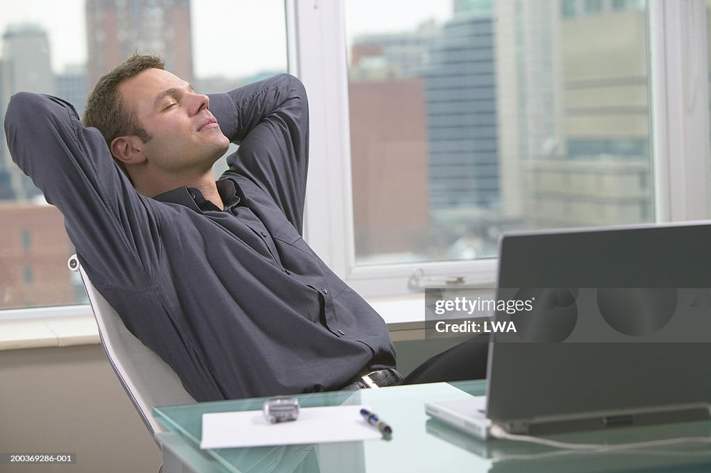 Man leaning back at desk, eyes shut