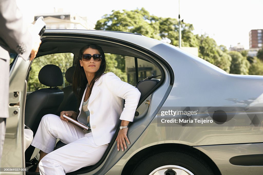 Young businesswoman getting out of back seat of car