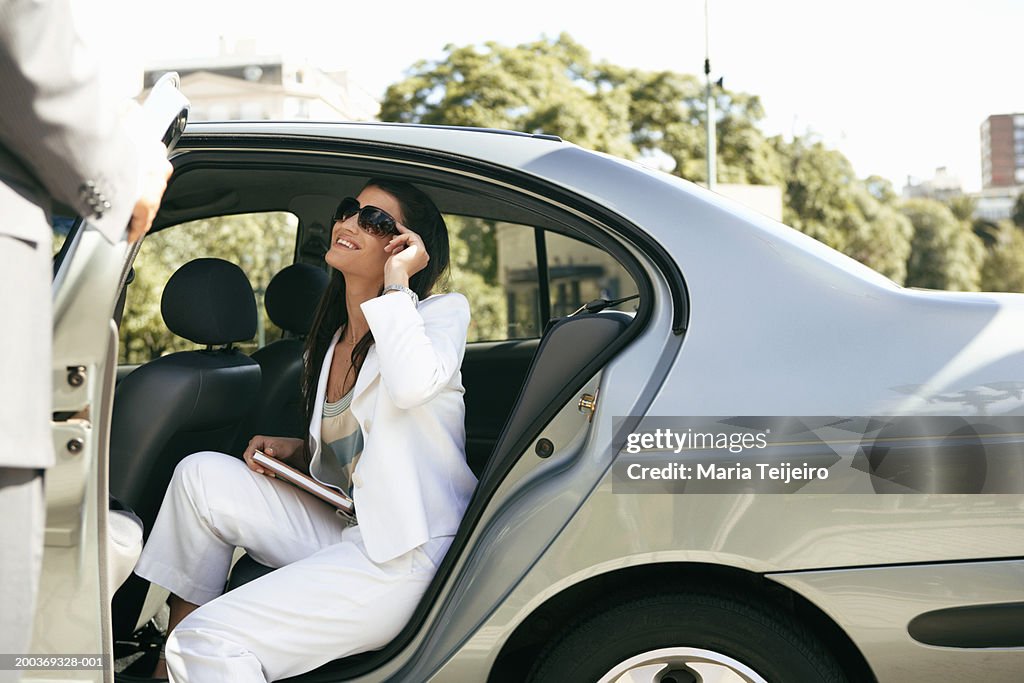 Young businesswoman in back seat of car smiling at man