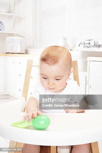 baby girl (6-9 months) in high chair playing with rattle, close-up - high chair stock pictures, royalty-free photos & images