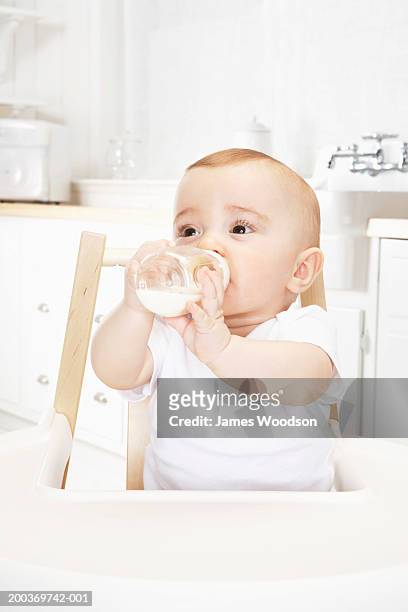 baby girl (6-9 months) drinking bottle in high chair, close-up - high chair stock pictures, royalty-free photos & images