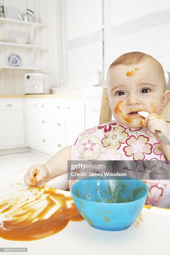 Baby girl (6-9 months) eating baby food, portrait, close-up