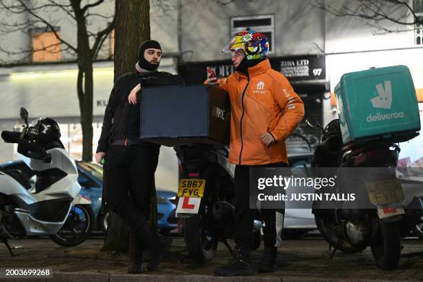 Takeaway delivery drivers gather at Notting Hill Gate in west London on February 14 during a strike to demand better pay and conditions. Britain's...