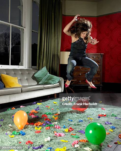 young woman jumping on balloons in living room - balloon woman party stock pictures, royalty-free photos & images