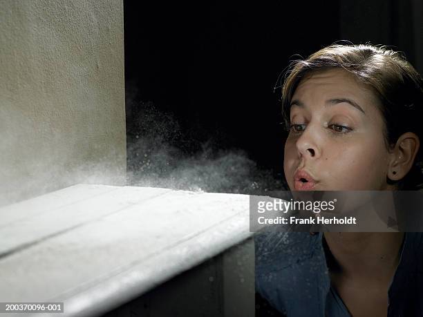young woman blowing dust off shelf - dust stock pictures, royalty-free photos & images