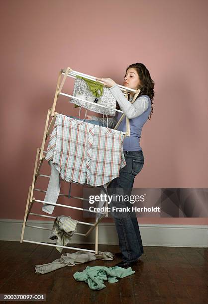 young woman carrying clothes horse indoors - wäscheständer stock-fotos und bilder