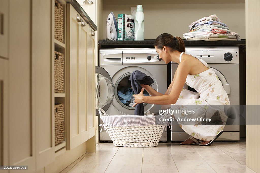 Woman loading washing machine in kitchen