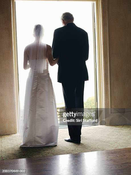 bride and father standing by doorway, rear view - bride father stock-fotos und bilder