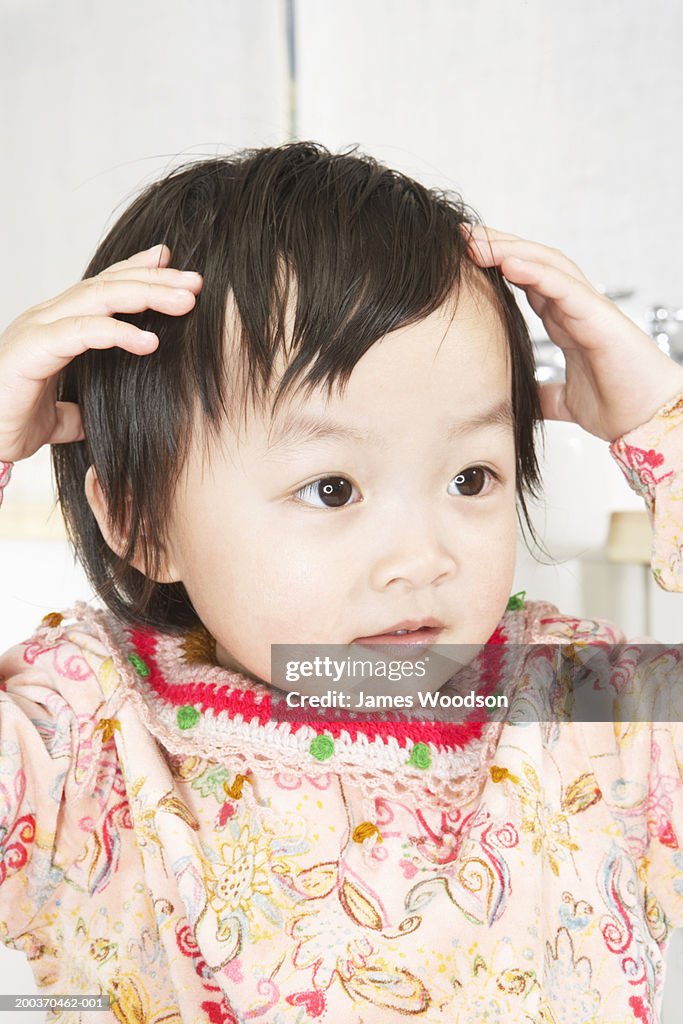 Toddler girl (21-24 months) touching head, close-up