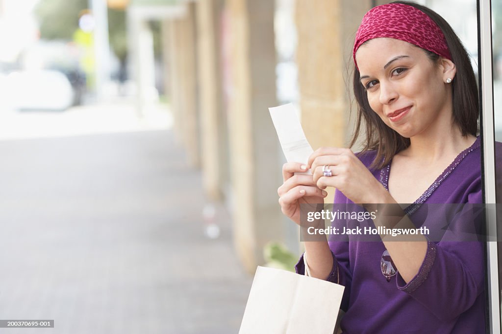Portrait of a young woman holding a receipt