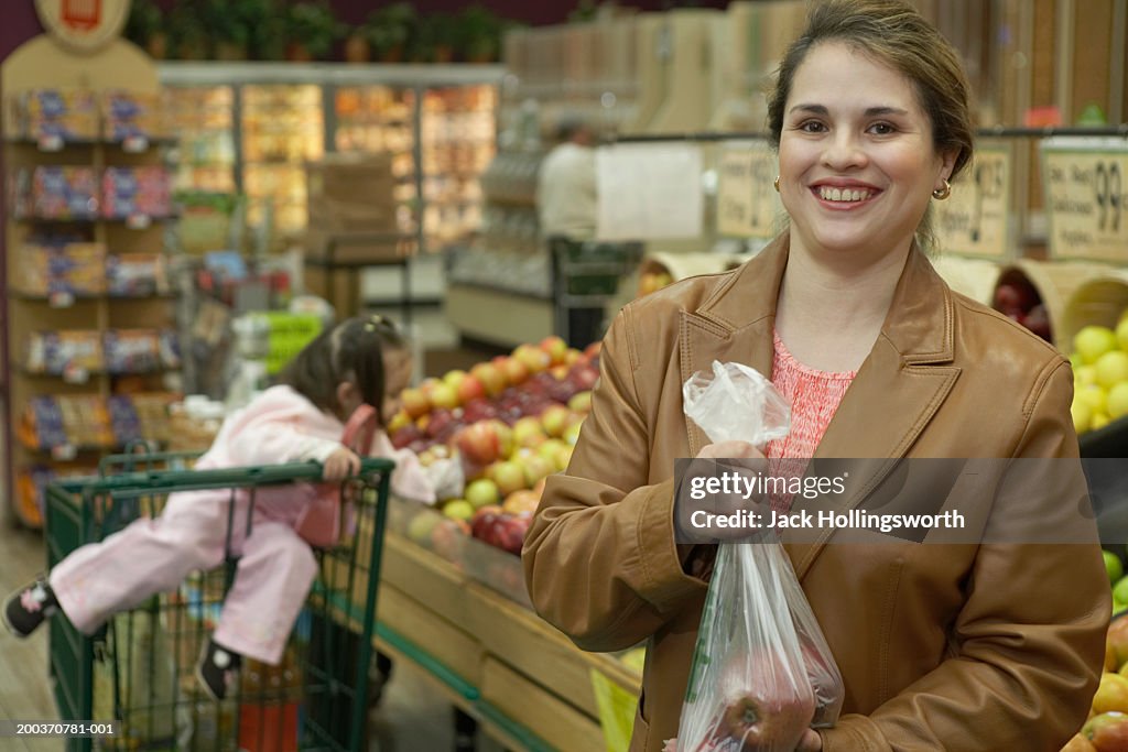 Mid adult woman holding a plastic bag with apples