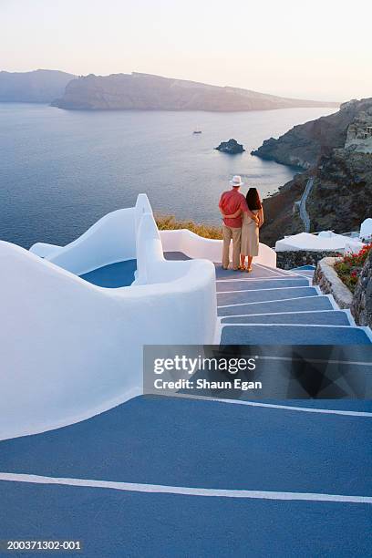 greece, the cyclades, santorini, couple embracing on steps, rear view - greece holiday foto e immagini stock