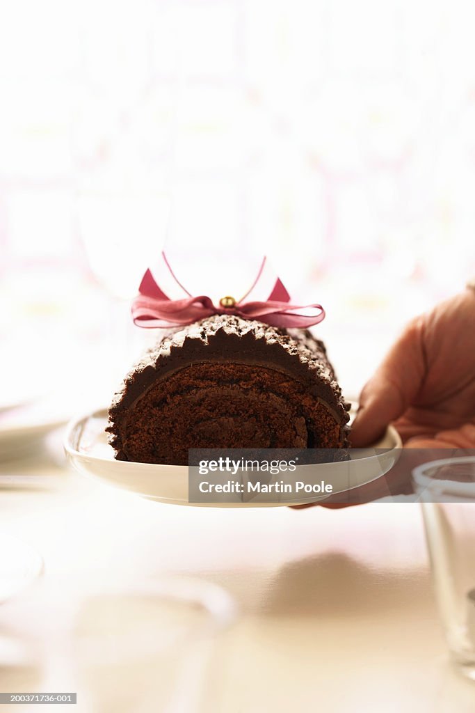 Woman holding yule log on plate, close up