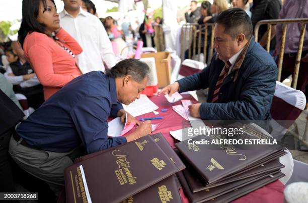Man signs his marriage certificate during a collective wedding celebration at the esplanade of the Municipal Palace of Nezahualcoyotl in...